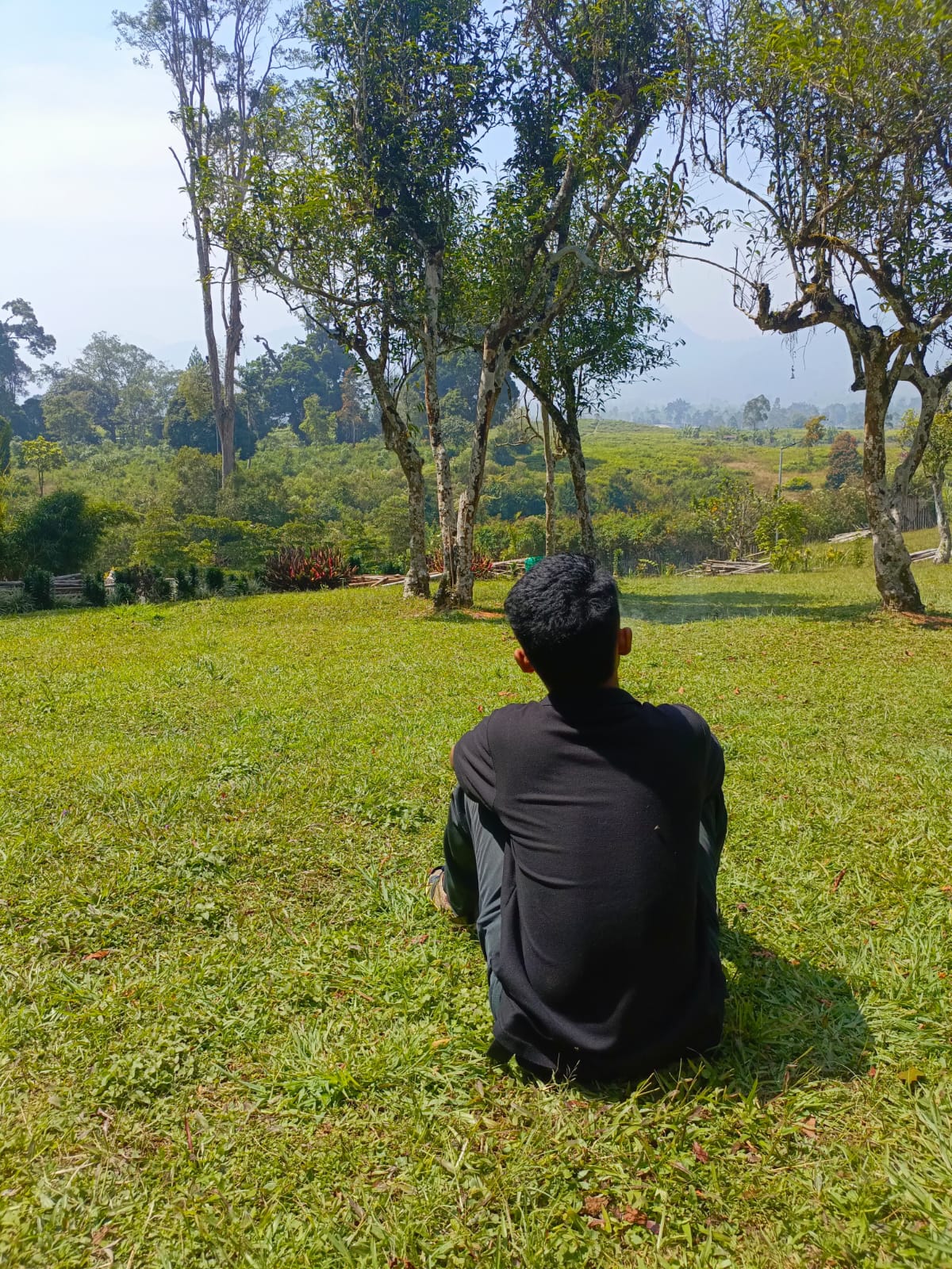 Foto Irsyad duduk di area hijau dengan pepohonan